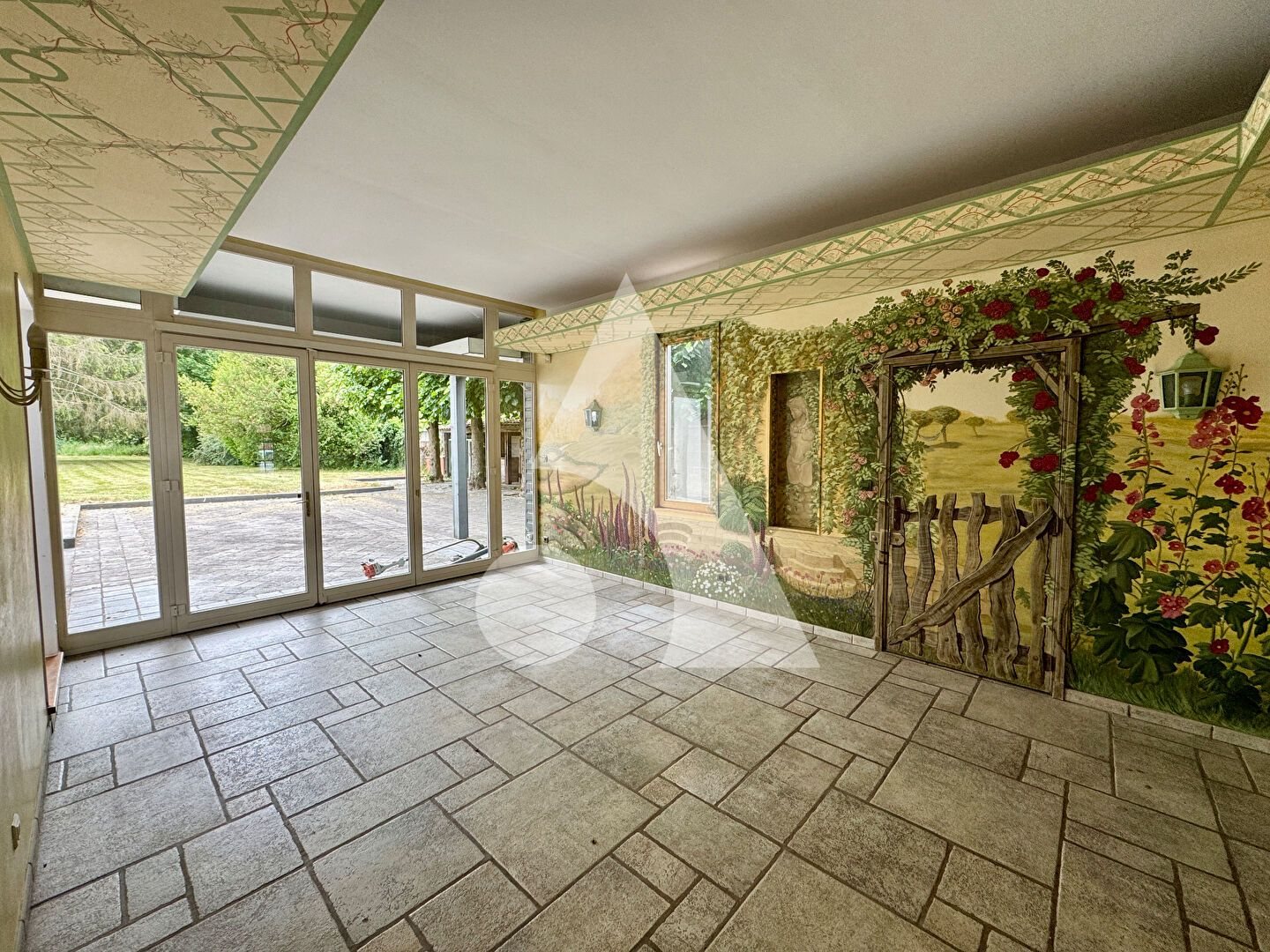 Grande salle avec fresque murale végétale et baies vitrées sur le jardin — futur espace de groupe du cabinet d'Escautpont